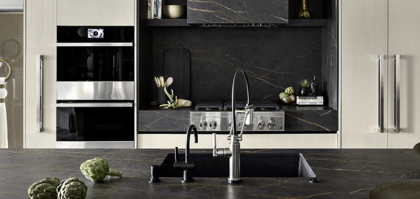 A modern kitchen with black marble counter and backsplash.